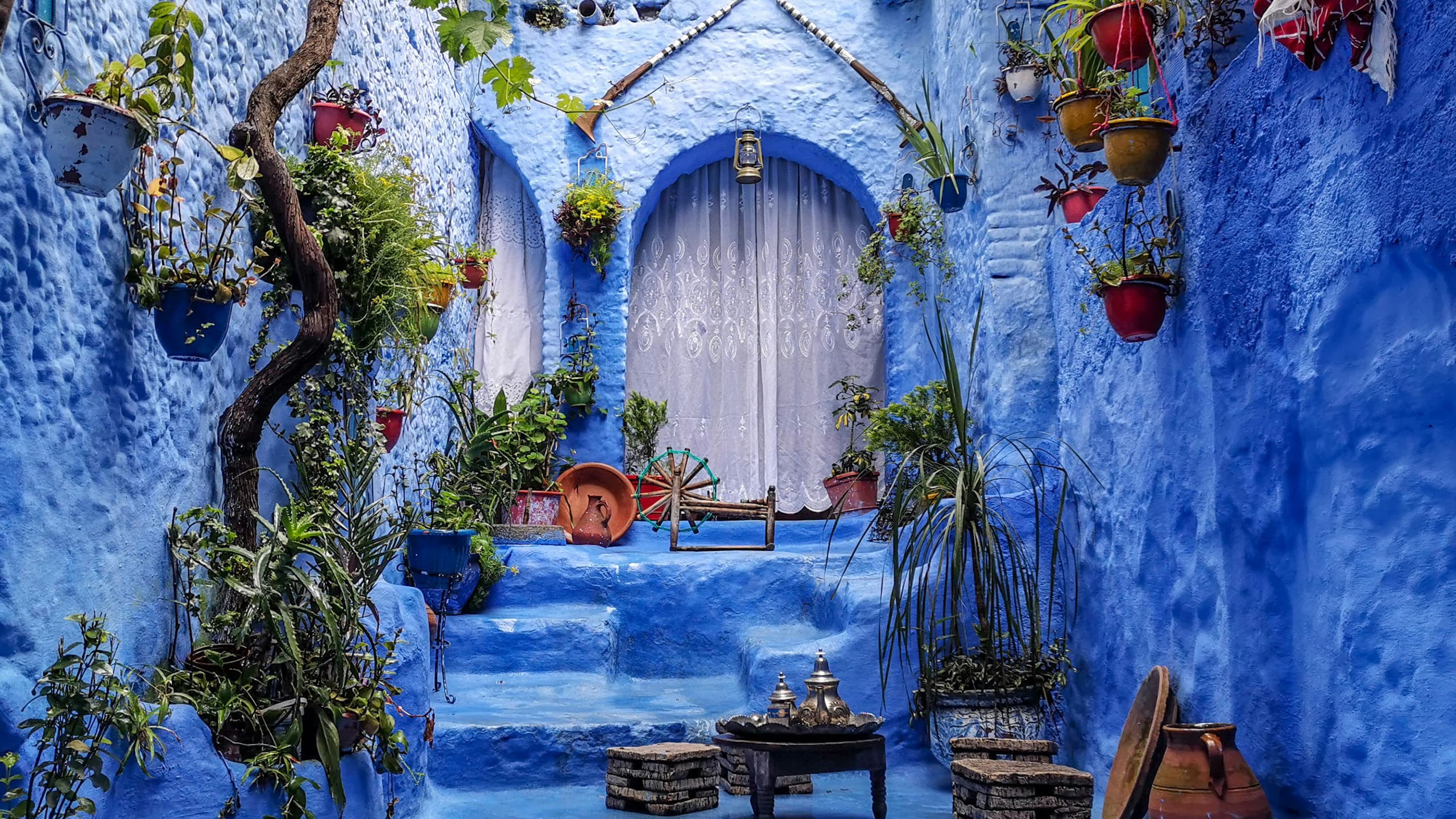 blaue Gasse mit Blumen und marrokanischer Tür aus Holz