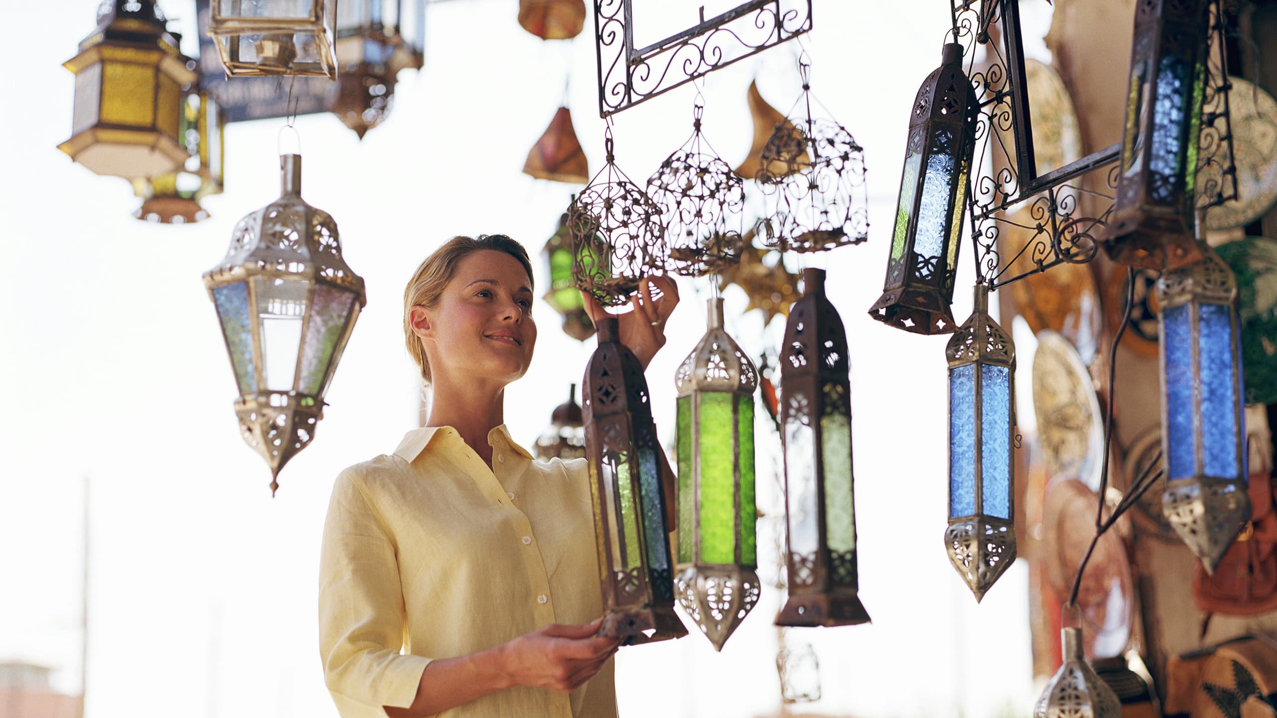 Eine lächelnde Frau an einem orientalischen Lampen-Marktstand